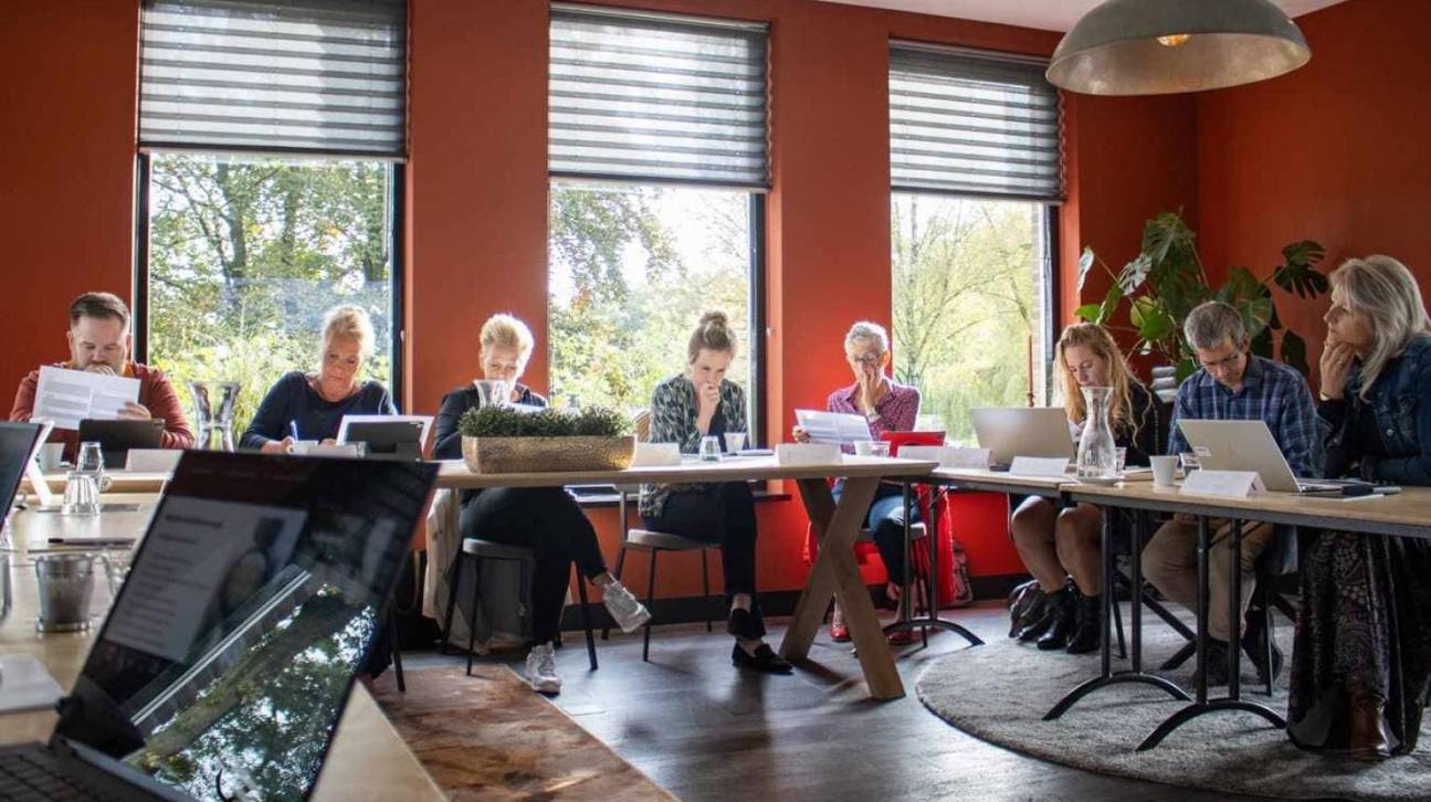 Schrijfsessie, mensen aan lange tafel aan het schrijven