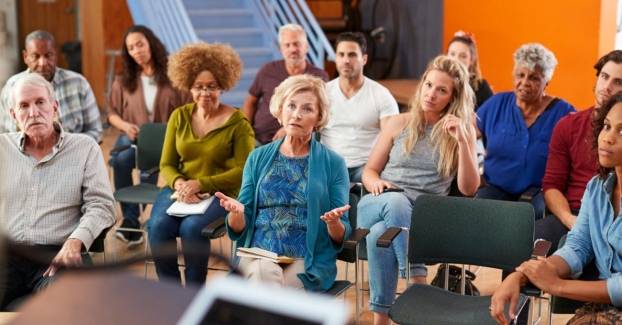 Toehoorders in een zaal voeren een discussie met de gespreksleider